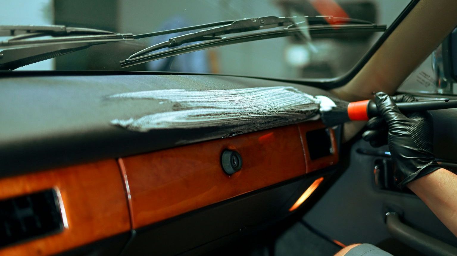 Man cleaning car dashboard with brush